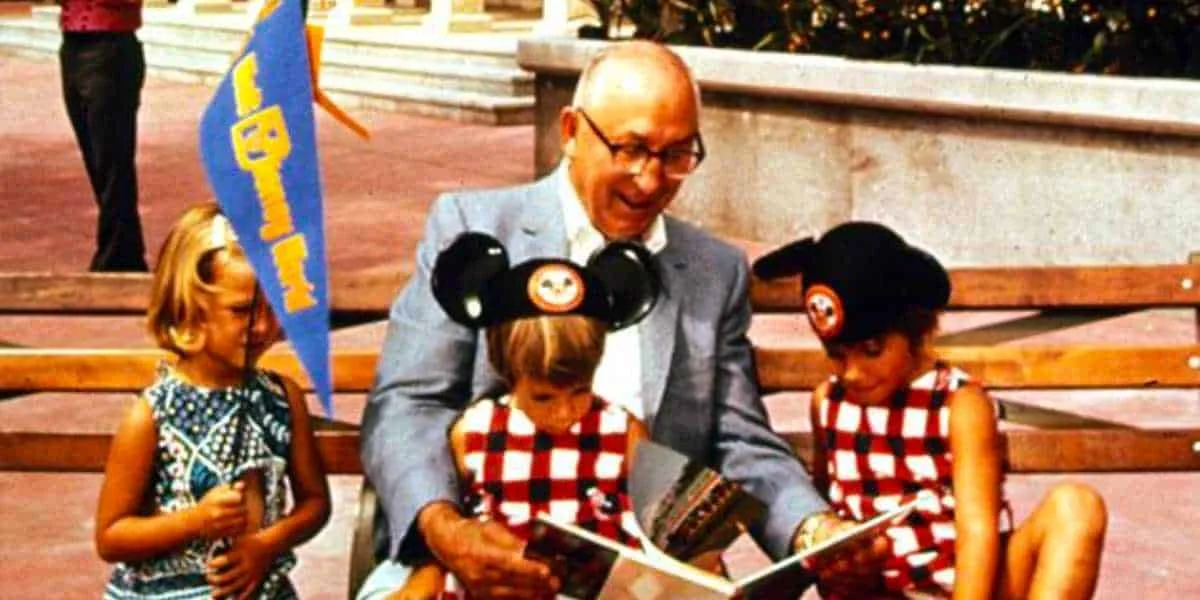 Roy O. Disney reading a book to children on a bench at Walt Disney World Resort