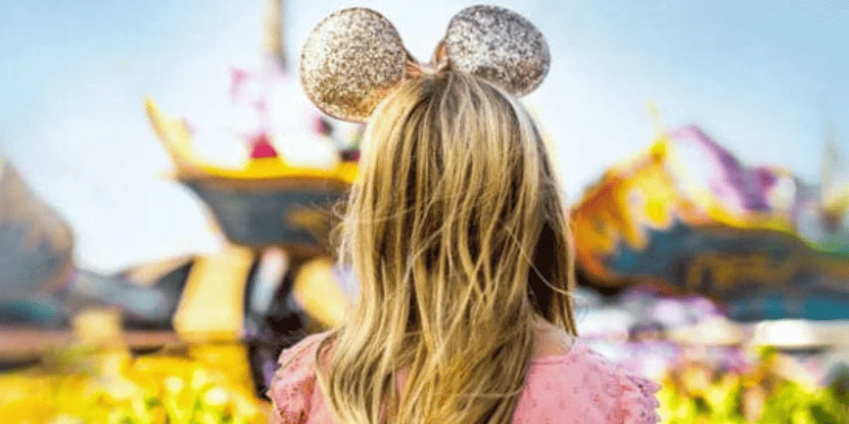 A woman wearing rose gold Minnie ears - a popular disney souvenir - in Fantasyland.