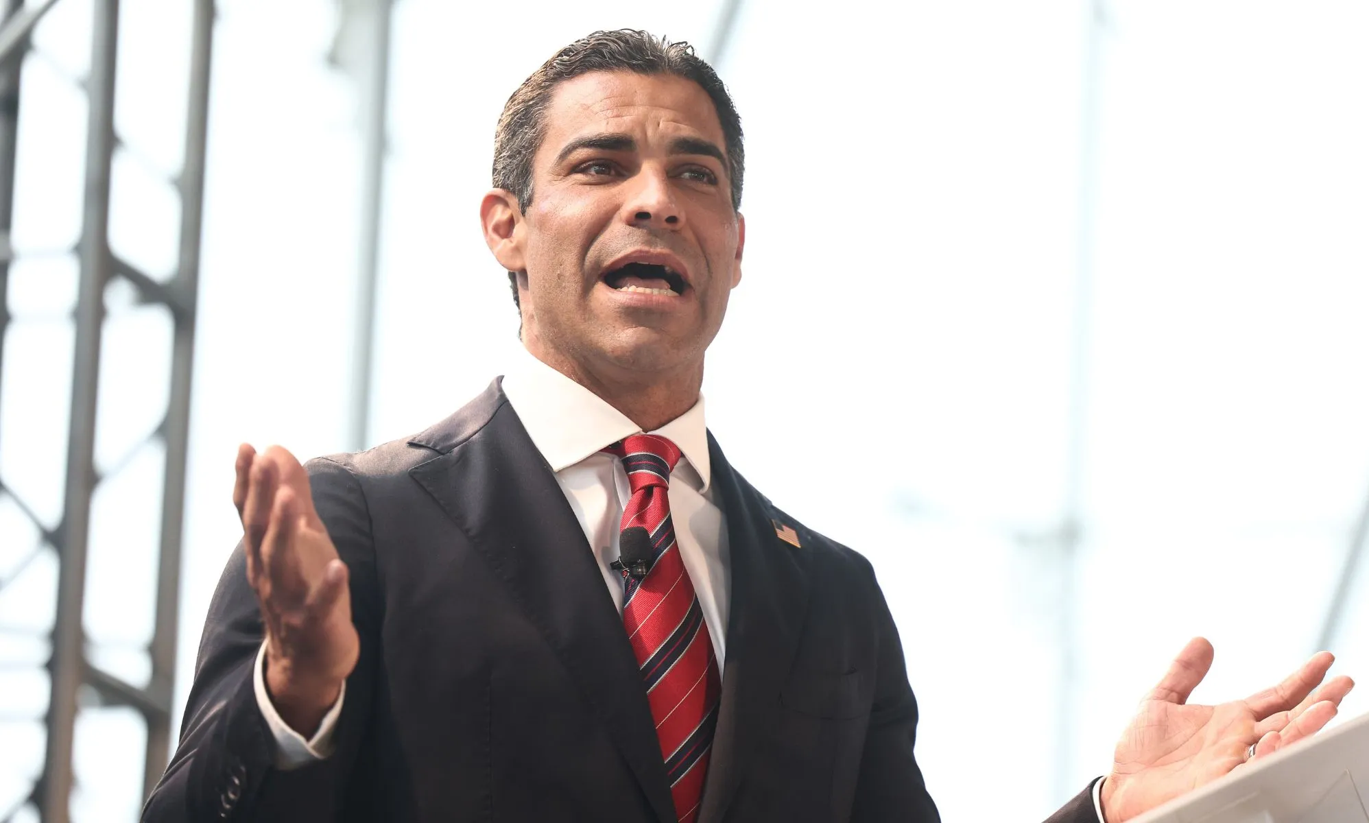 Francis Suarez, who is a 2024 Republican presidential candidate, wears a white shirt, red and blue striped tie and dark suit jacket as he speaks to people off camera