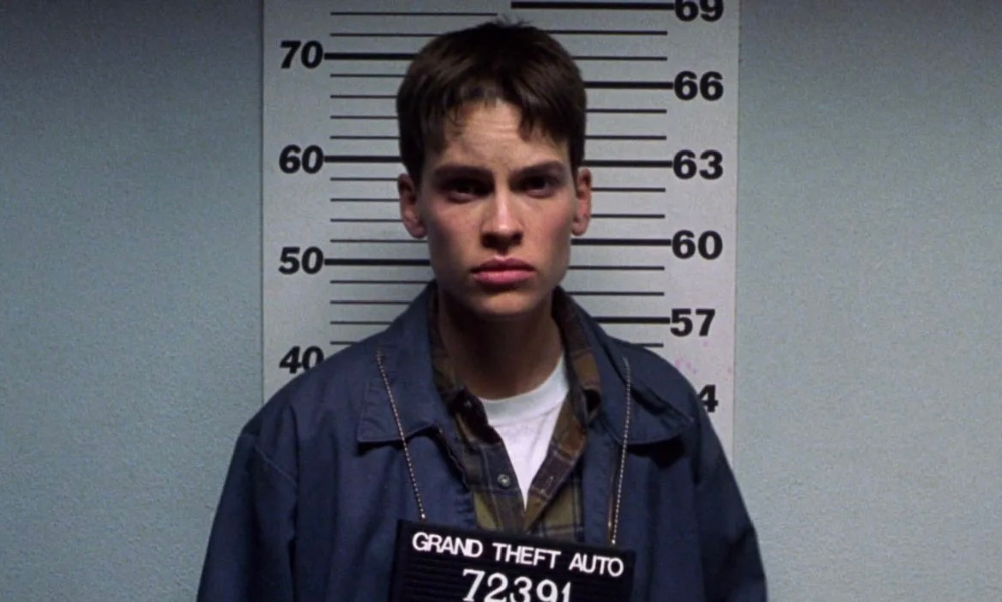 Hilary Swank as Brandon Teena getting a mugshot in Boys Don't Cry.