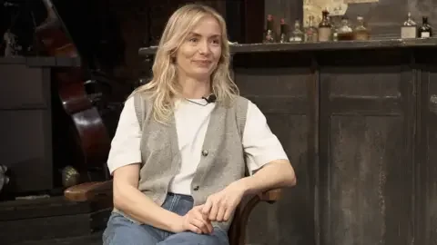 Sophie Melville, sitting in front of a dingy dive bar