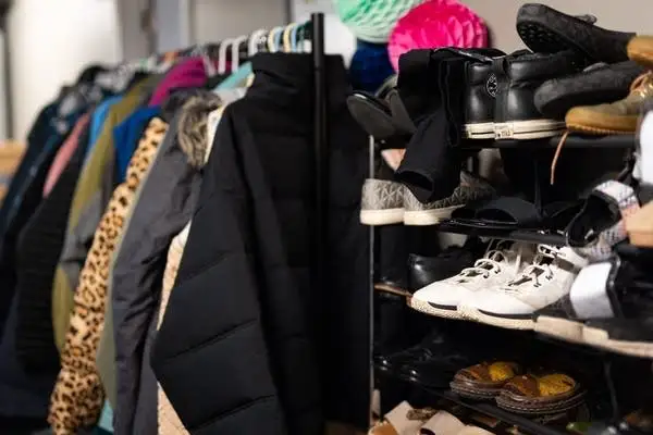 Shoes sit on shelves and clothes on a rack