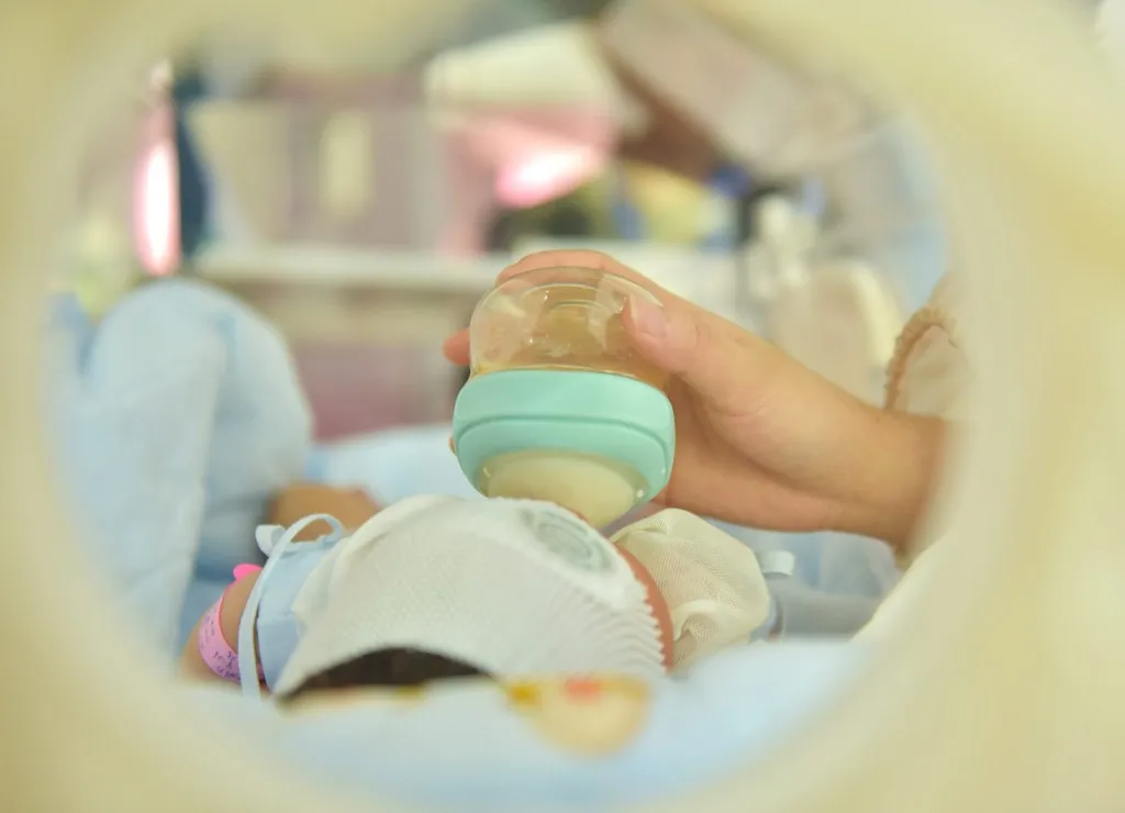 A medical worker breastfeeds a newborn.