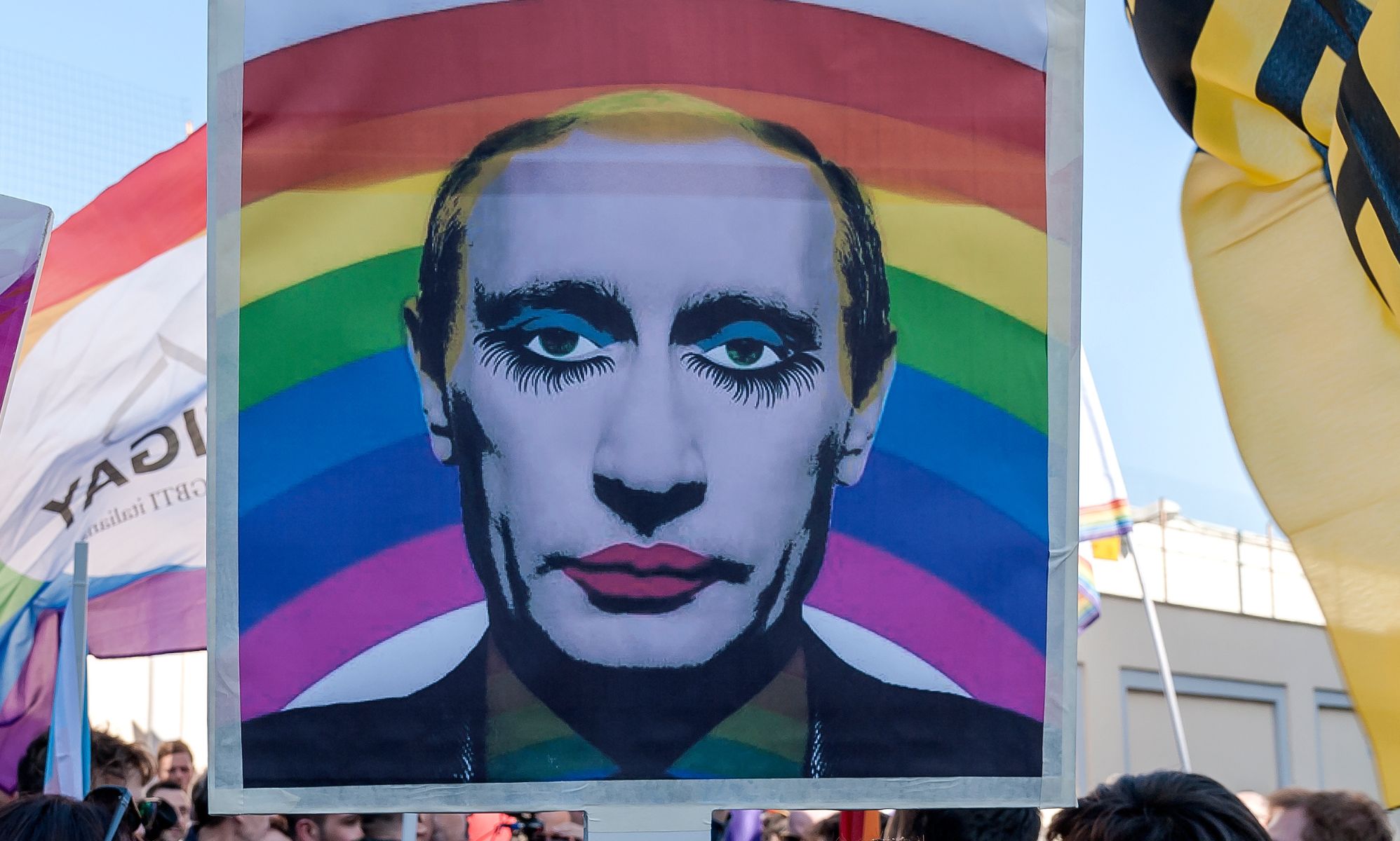 A protestor holding up a modified picture of Vladimir Putin wearing makeup.