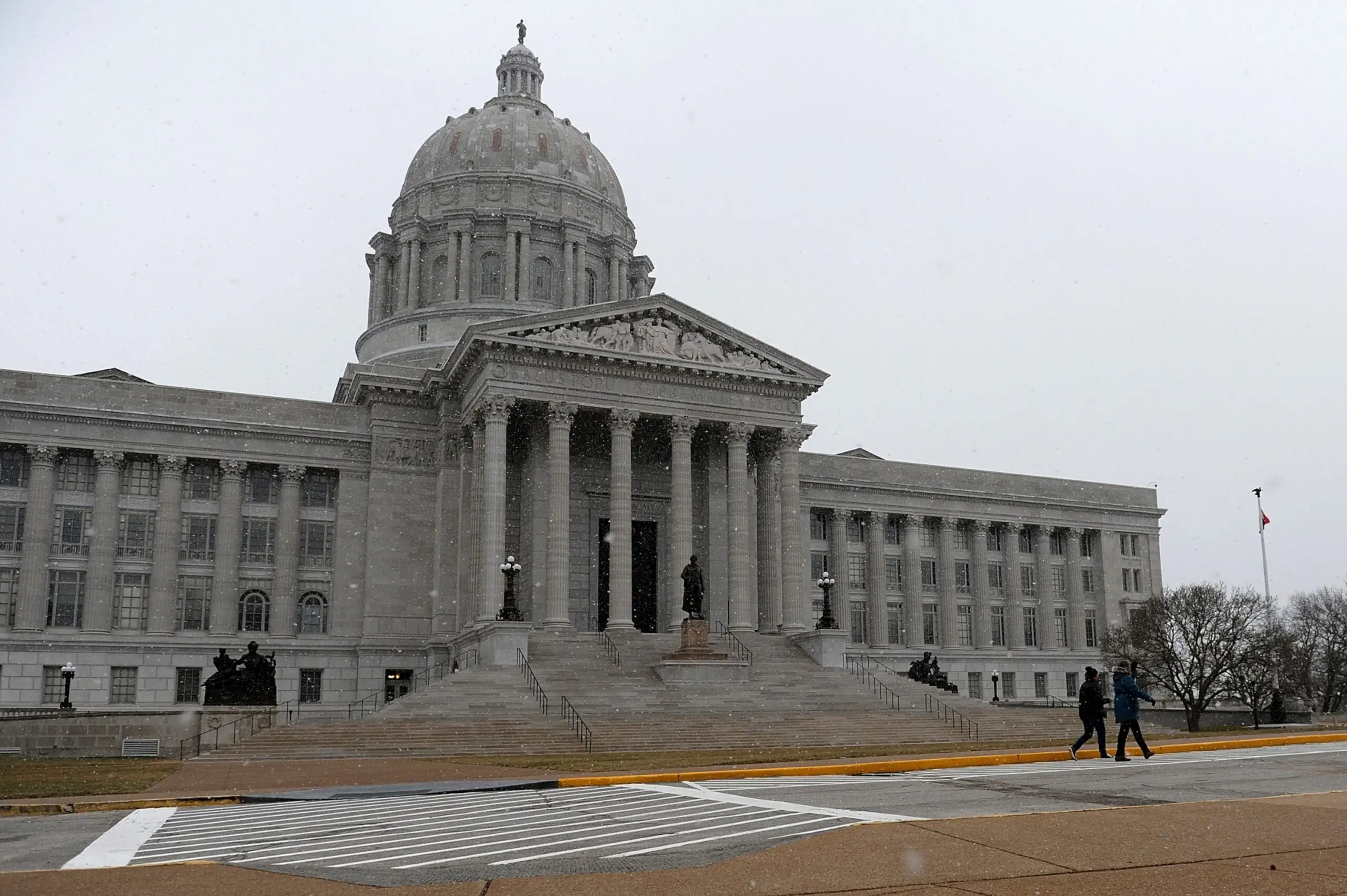 PHOTO: On January 17, 2021, walkers in Jefferson City, Missouri, watch as snow flakes fall outside the Missouri State Capitol Building.