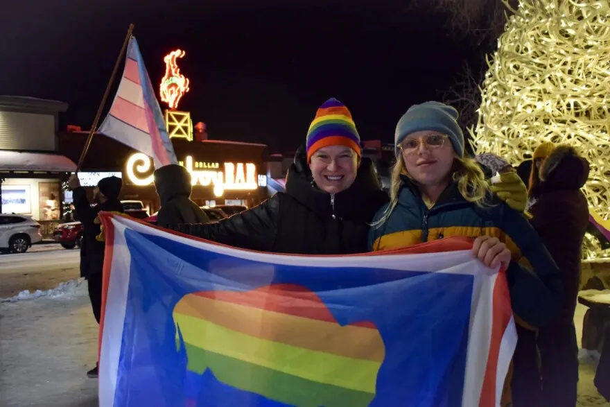 Kjera Griffith and her daughter, Augie Henrie, hold up a Wyoming state flag in the pride colors. 