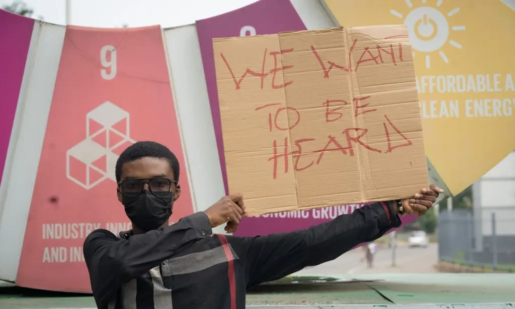 LGBTQ+ activist Prince Frimpong holds up a sign reading 'we want to be heard' while protesting anti-LGBTQ+ sentiment in Ghana