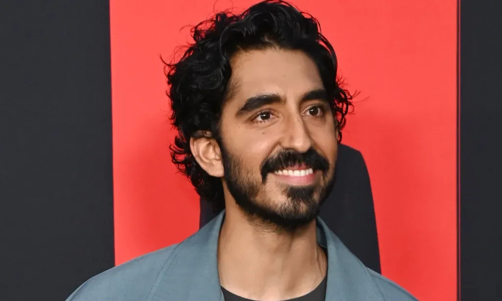 Dev Patel smiling during a red carpet event at the Monkey Man premiere.