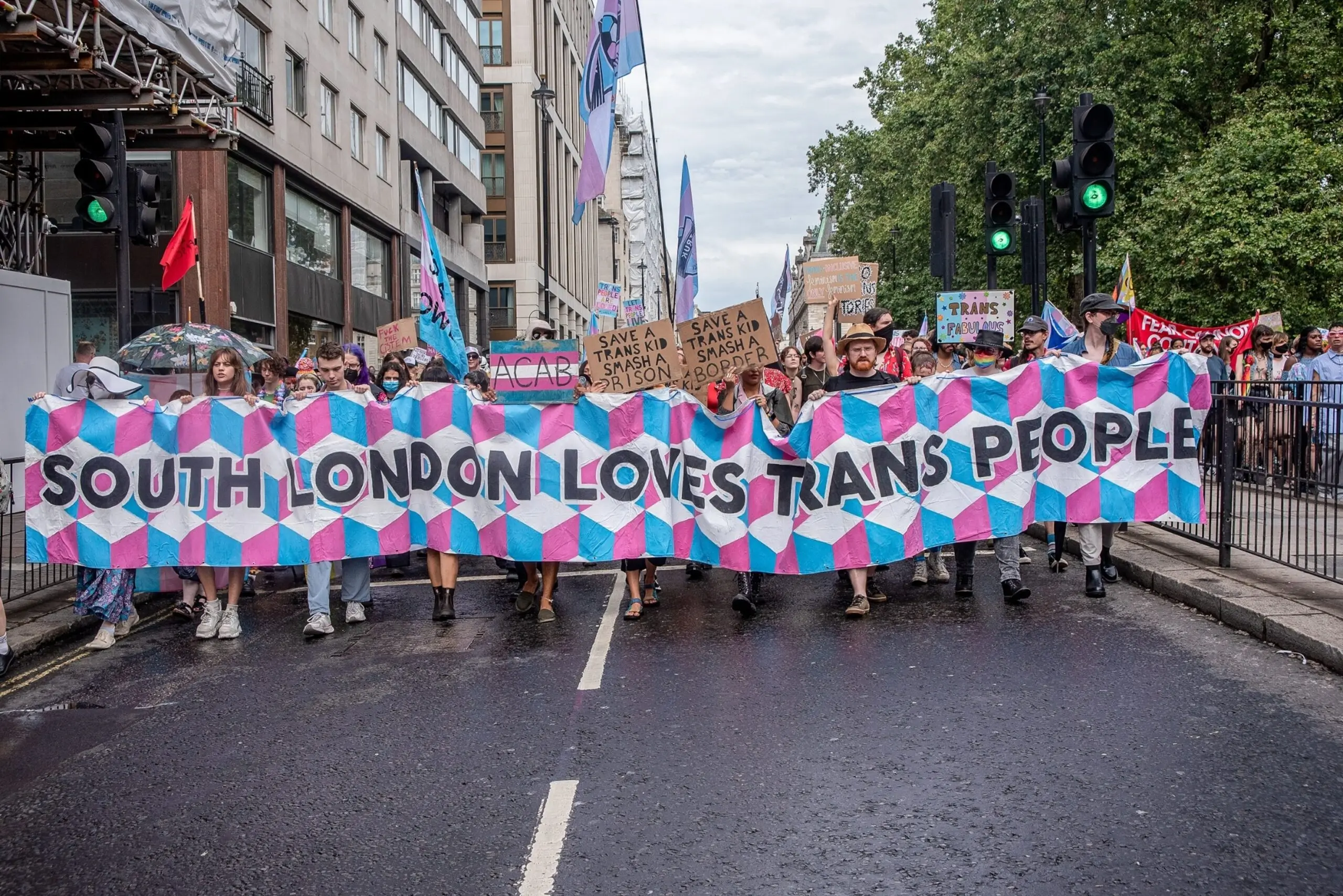 PHOTO: Trans activists and protesters hold a banner and placards while marching towards the Hyde Park Corner, July 8, 2023.