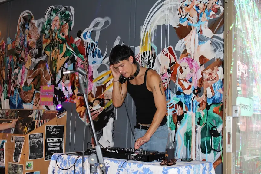 A DJ plays in a room with graffiti on the walls.