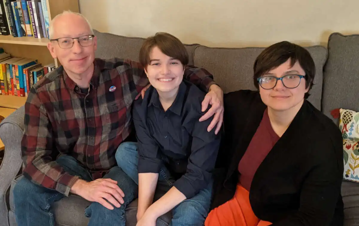 Puck Carlson poses with their parents, Richard and Ulrike Carlson, at their home in Iowa City.