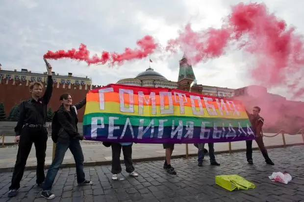 Activists hold a rainbow colored banner.