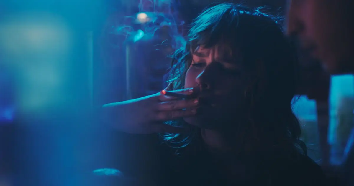 A young person smokes a cigarette in a blue-filtered image from T-Blockers