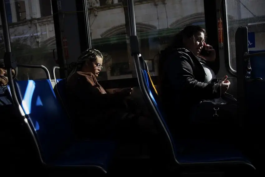 On Nov. 21, 2023, Isabella Morningstar looks at her phone on the bus on her way to Palo Alto College, which is 10 miles south of the youth shelter where she is staying.