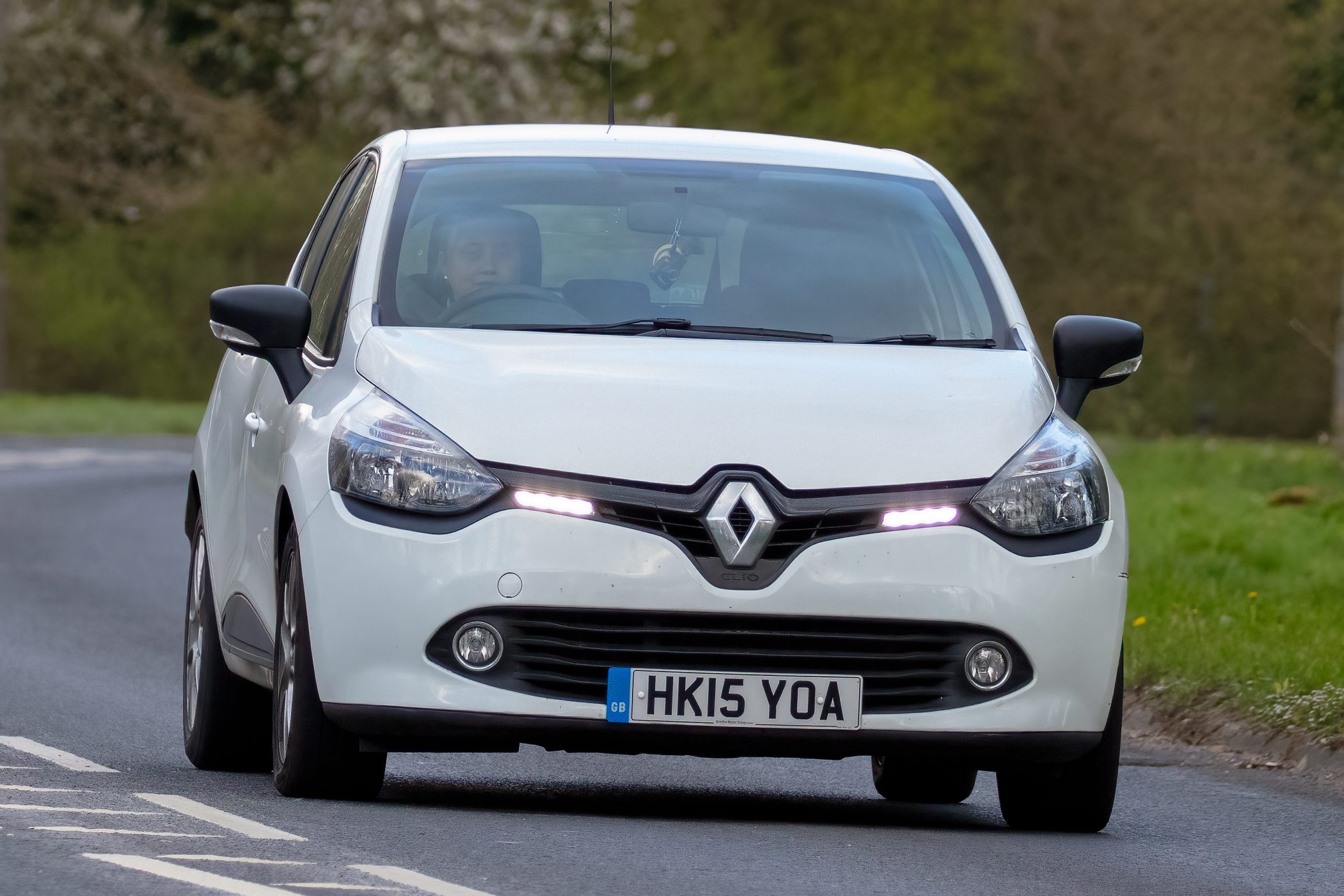 A 2015 white Renault Clio travels along an English country road