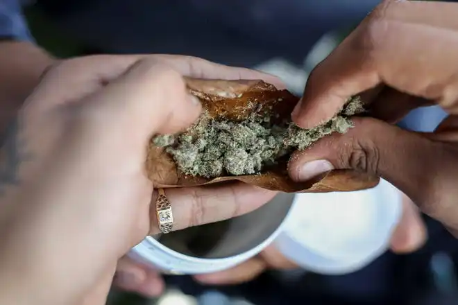 People roll a blunt during the informal annual cannabis holiday in Denver on April 20, 2023.