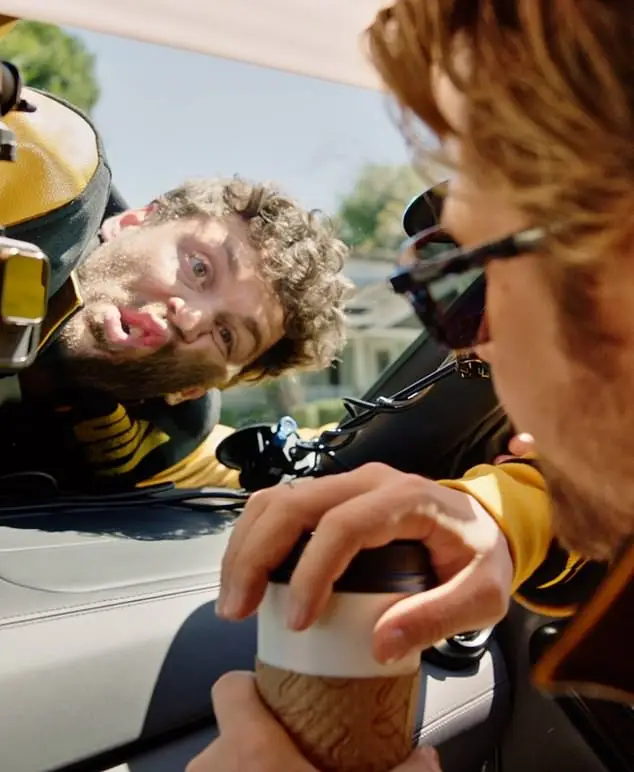 The actor jumps behind the wheel of a neon green car, tasked with picking up his fellow stuntmen and taking them to the set to film the action comedy