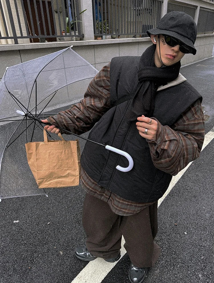 korean men's fashion: Black Puffer Vest Layered over Brown Plaid Oversized Shirt + Dark Brown Baggy Pants + Black Bucket Hat + Black Sunglasses + Black Scarf + Black Sneakers