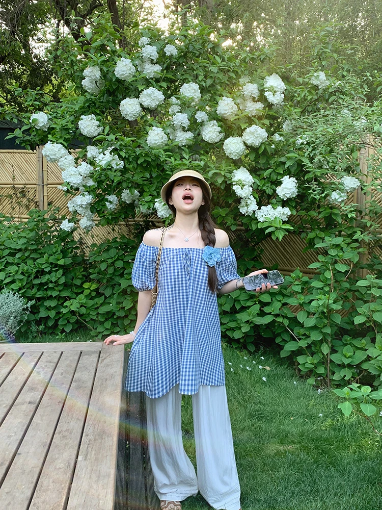 Bucket Hat + Blue Gingham Off-Shoulder Tunic + Oversize Floral Pin + White Wide-Leg Palazzo Pants + Straw Slide Sandals