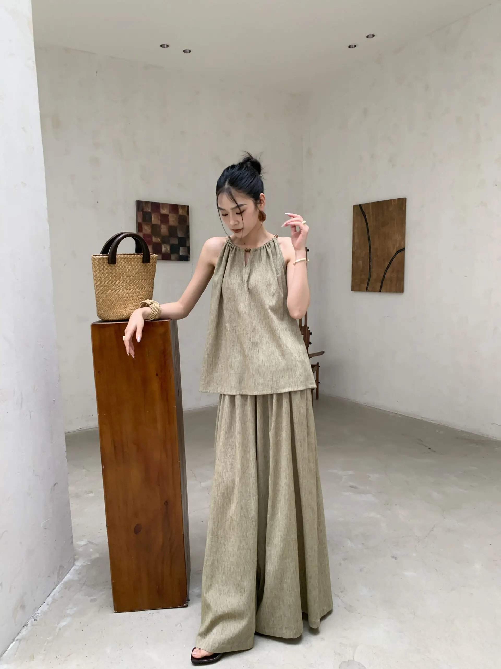 Messy high bun + khaki drawstring halter + matching ultra-wide trousers + straw basket