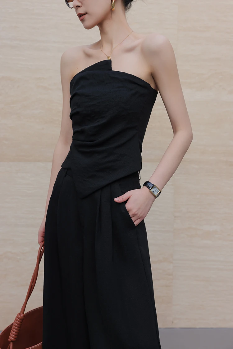 Sleek bun + strapless black asymmetric top + pleated wide-leg trousers + leather tote