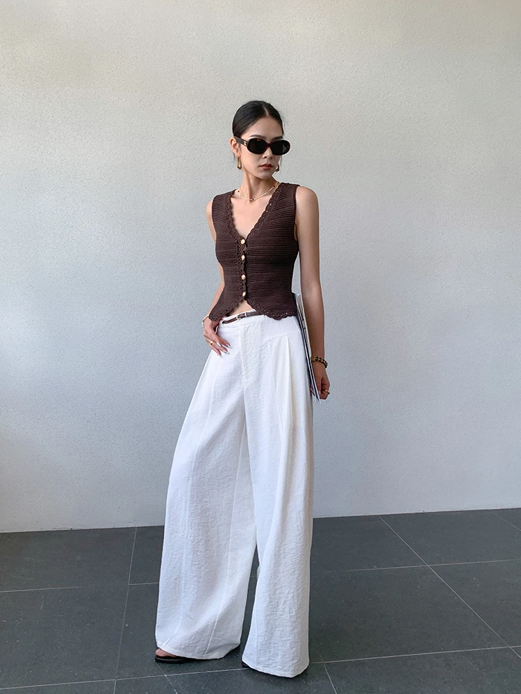 Loose top-knot + olive drawstring halter + ultra-wide palazzo pants + structured straw bucket