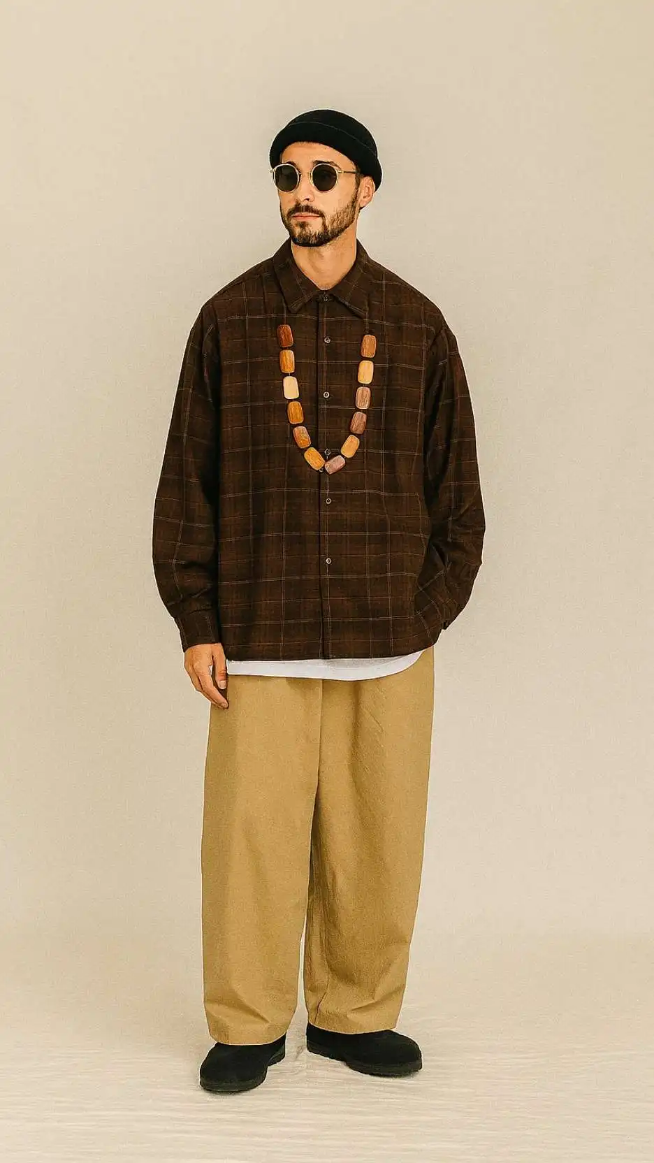 Black Knit Beanie + Brown Plaid Overshirt + Chunky Wood-Bead Necklace + Long White Tee + Khaki Puddle Trousers + Black Suede Loafers