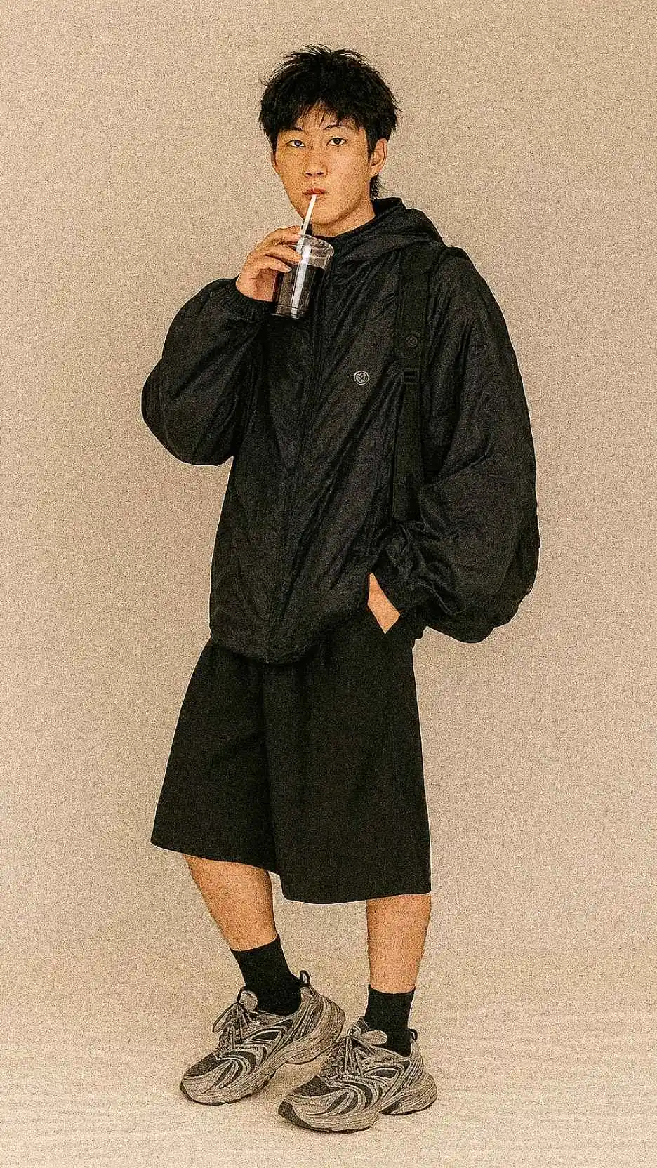 Oversized Black Windbreaker + Black Backpack + Knee-Length Wide Shorts + Chunky Grey Dad Sneakers + Black Crew Socks
