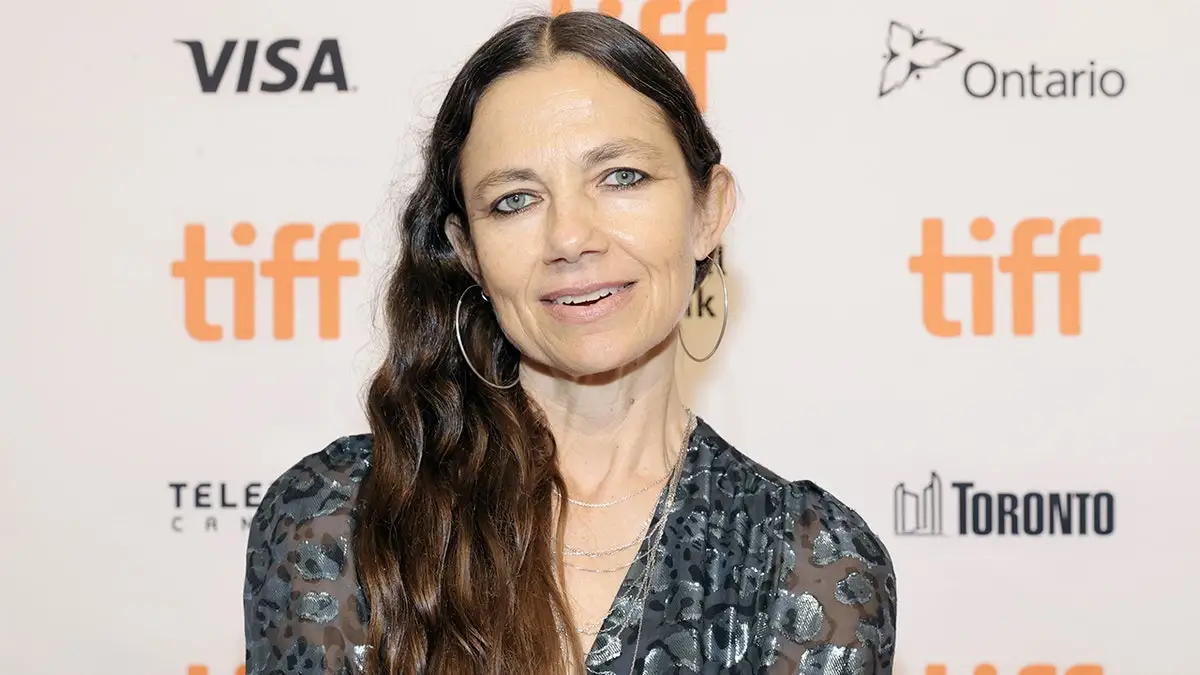 Justine Bateman smiles on the red carpet in Ontario in a printed top with transparent sleeves