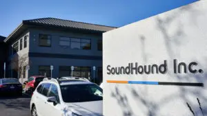 SOUN stock: SoundHound’s Headquarters exterior featuring a sign with the company’s logo in the foreground and a parking lot and building in the background.