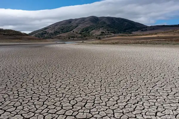 A cracked lake bed with mountain in background.