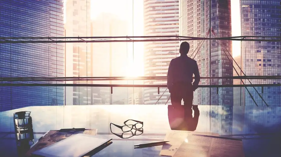 business man in glass office looking at cityscape