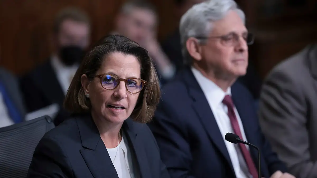 Lisa Monaco seated next to Garland during a DC crime presser