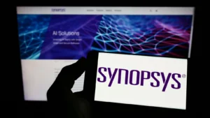 Person holding mobile phone with logo of American technology company Synopsys Inc. (SNPS) on screen in front of web page. Focus on phone display. Unmodified photo.